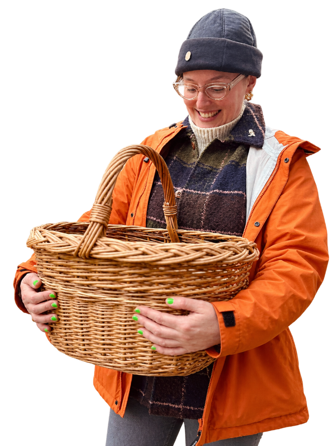 Smiling Caitlin in an orange jacket holding a wicker basket